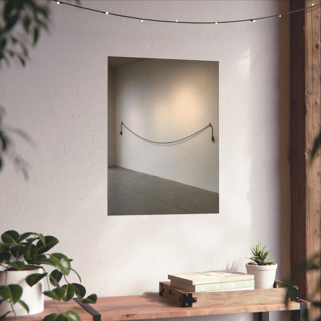 An extension cord hung in a long slack curve across a bare white wall. The Unplugged Line by Garabaggio, fine art print hanging in a room.