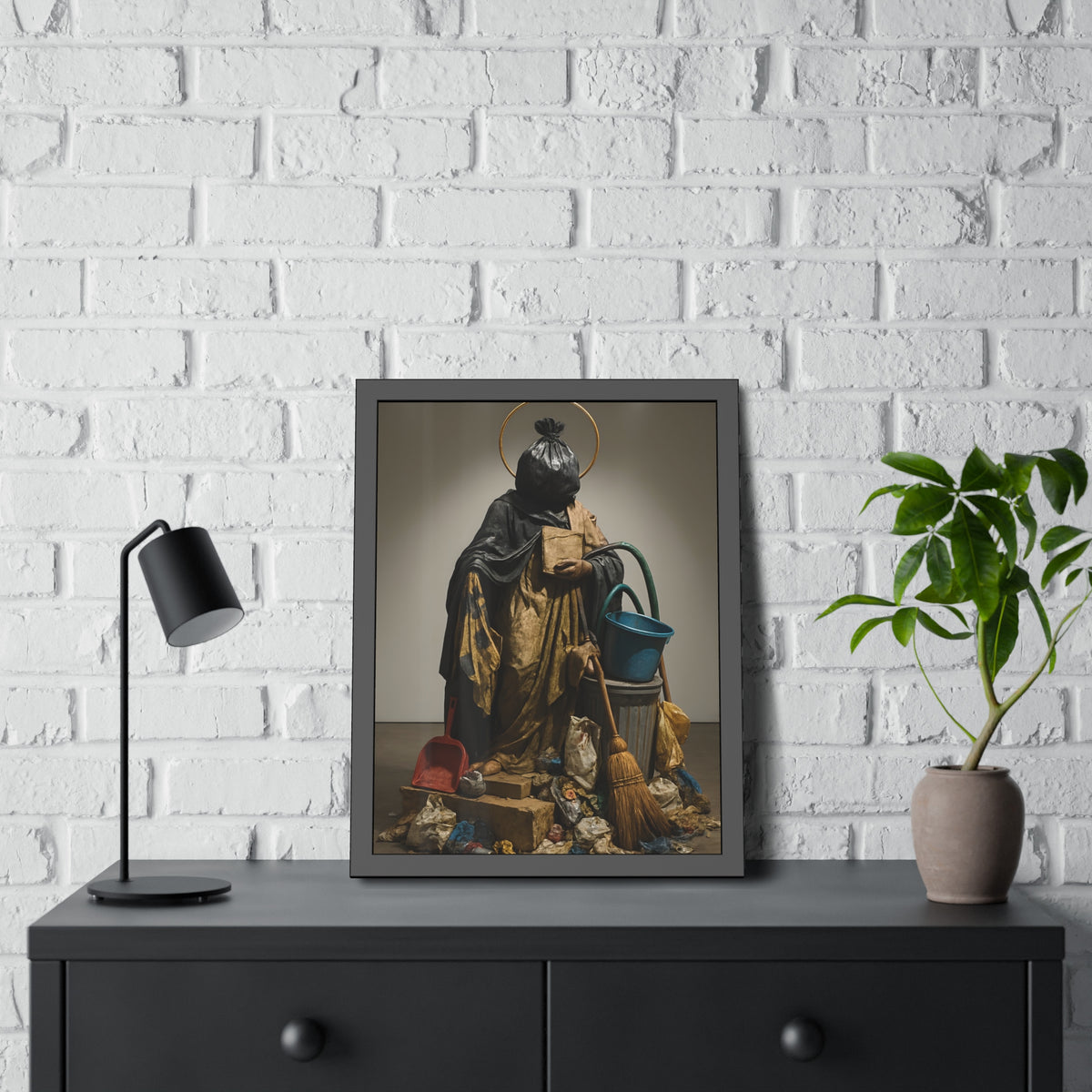 A robed figure with a garbage bag head and gold halo holding a broom. The Custodian Enthroned by Garabaggio, framed fine art print hanging in a room.