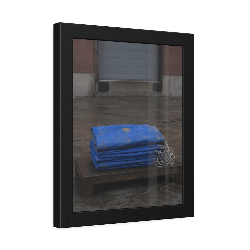 A folded blue tarp stacked on a low wooden platform by a loading dock. The Repaired Fold by Garabaggio, framed fine art print hanging in a room.