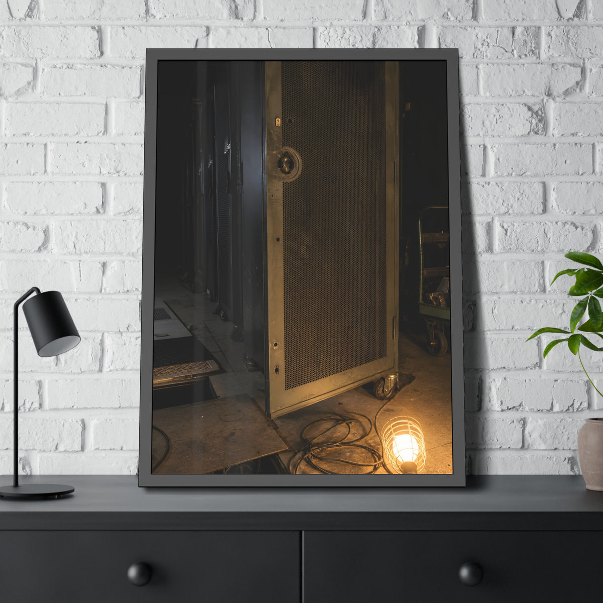 A perforated server rack door in a dark aisle lit by a floor work lamp. The Cold Aisle by Garabaggio, framed fine art print hanging in a room.