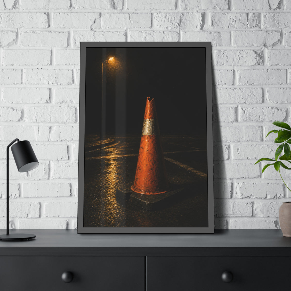 A battered orange traffic cone on wet asphalt under a street lamp. The Warning Without Danger by Garabaggio, framed fine art print hanging in a room.