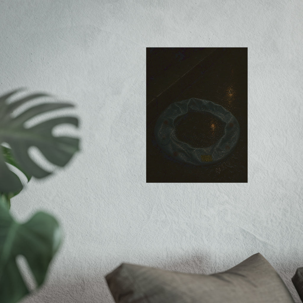 A deflated ring float holding rainwater on wet pavement at night. The Basin of Rain (Pool Float) by Garabaggio, fine art print hanging in a room.