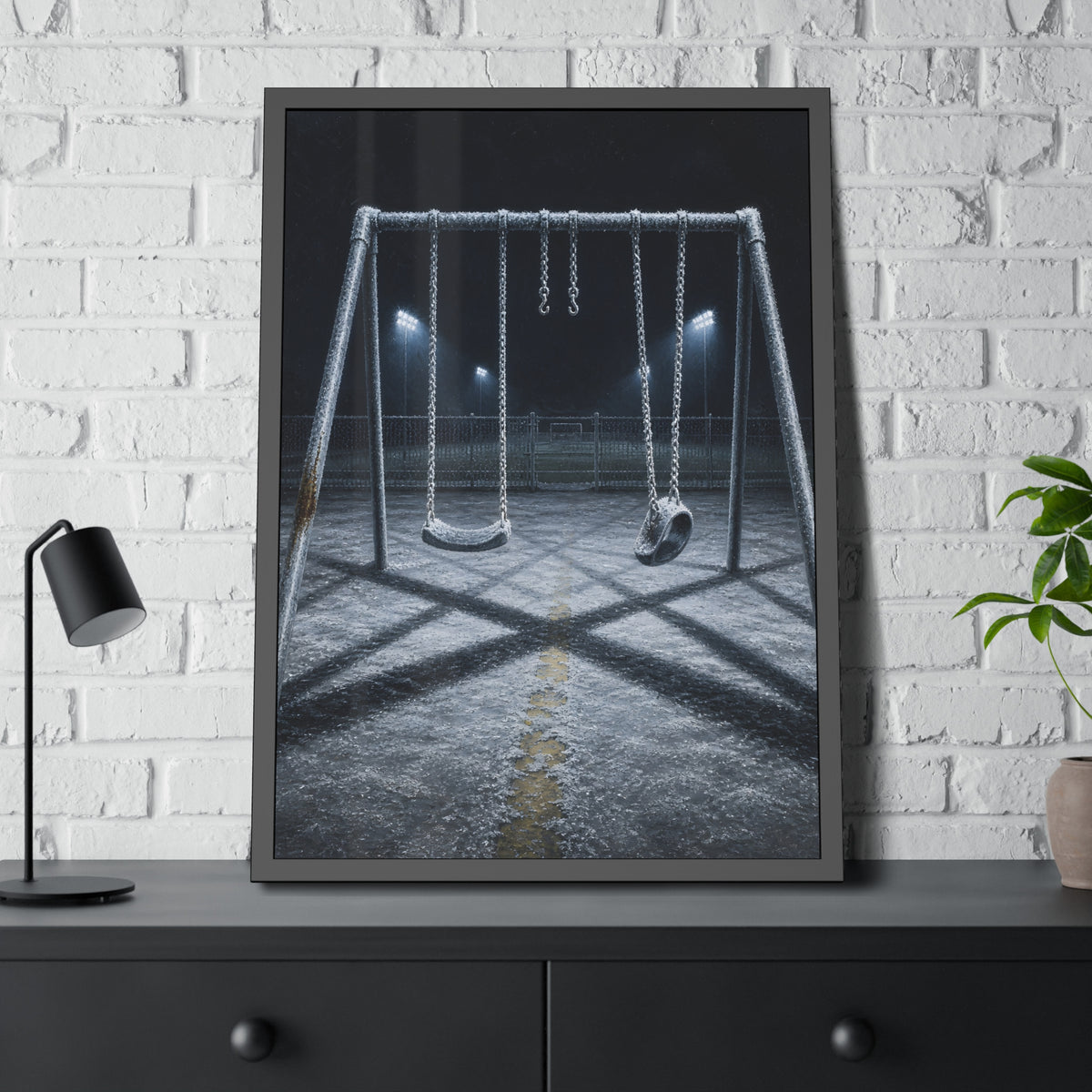 A frost covered swing set on empty asphalt under distant floodlights. The Third Hour: The Coldest Part by Garabaggio, framed fine art print hanging in a room.