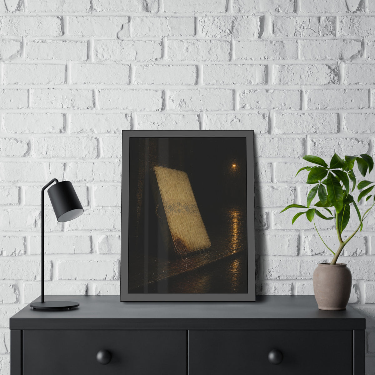 A stained mattress leaning against a wall in rain under a streetlamp. The First Rain by Garabaggio, framed fine art print hanging in a room.