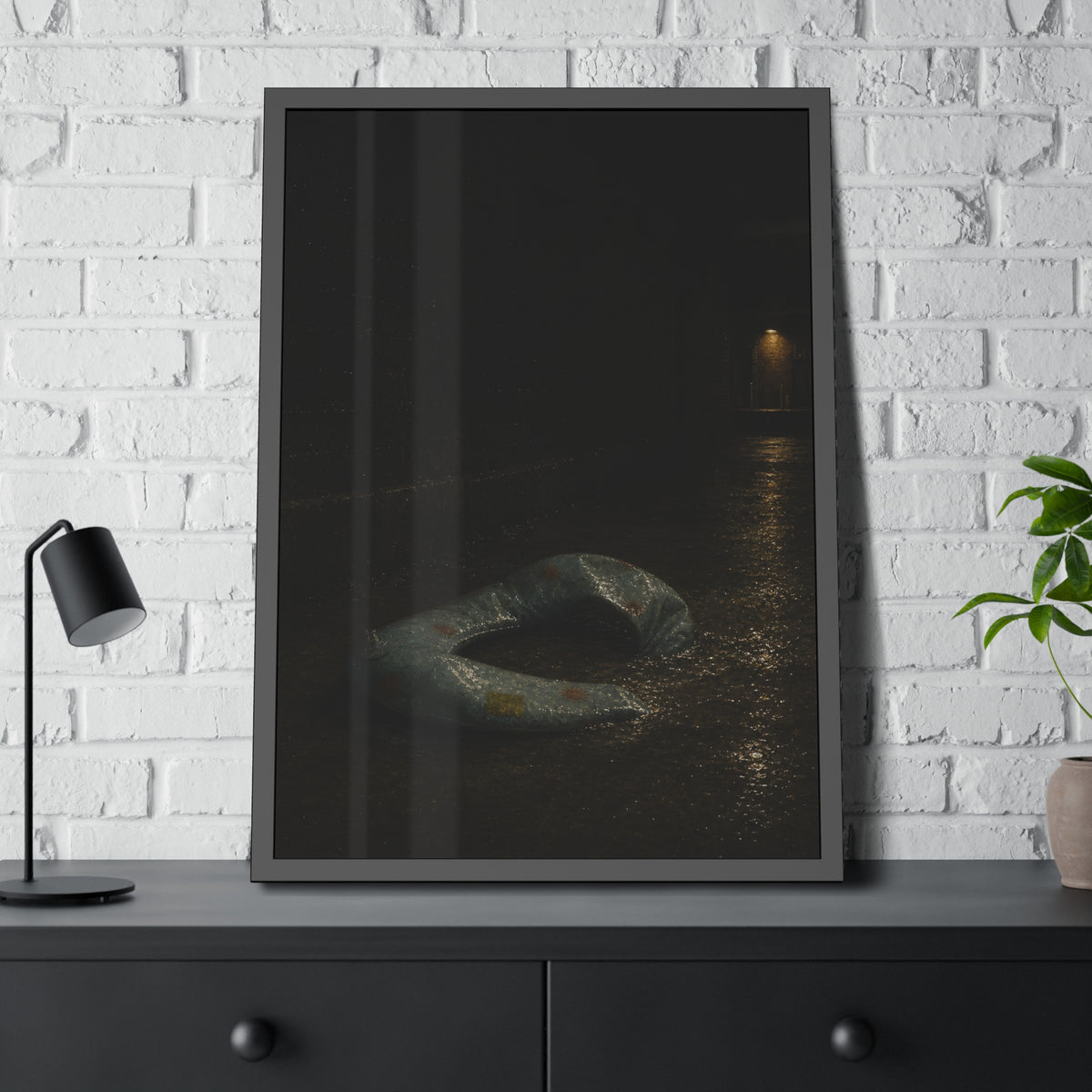 A deflated pool float ring on wet alley pavement, a lit doorway far behind. The Crossing of the Alley by Garabaggio, framed fine art print hanging in a room.
