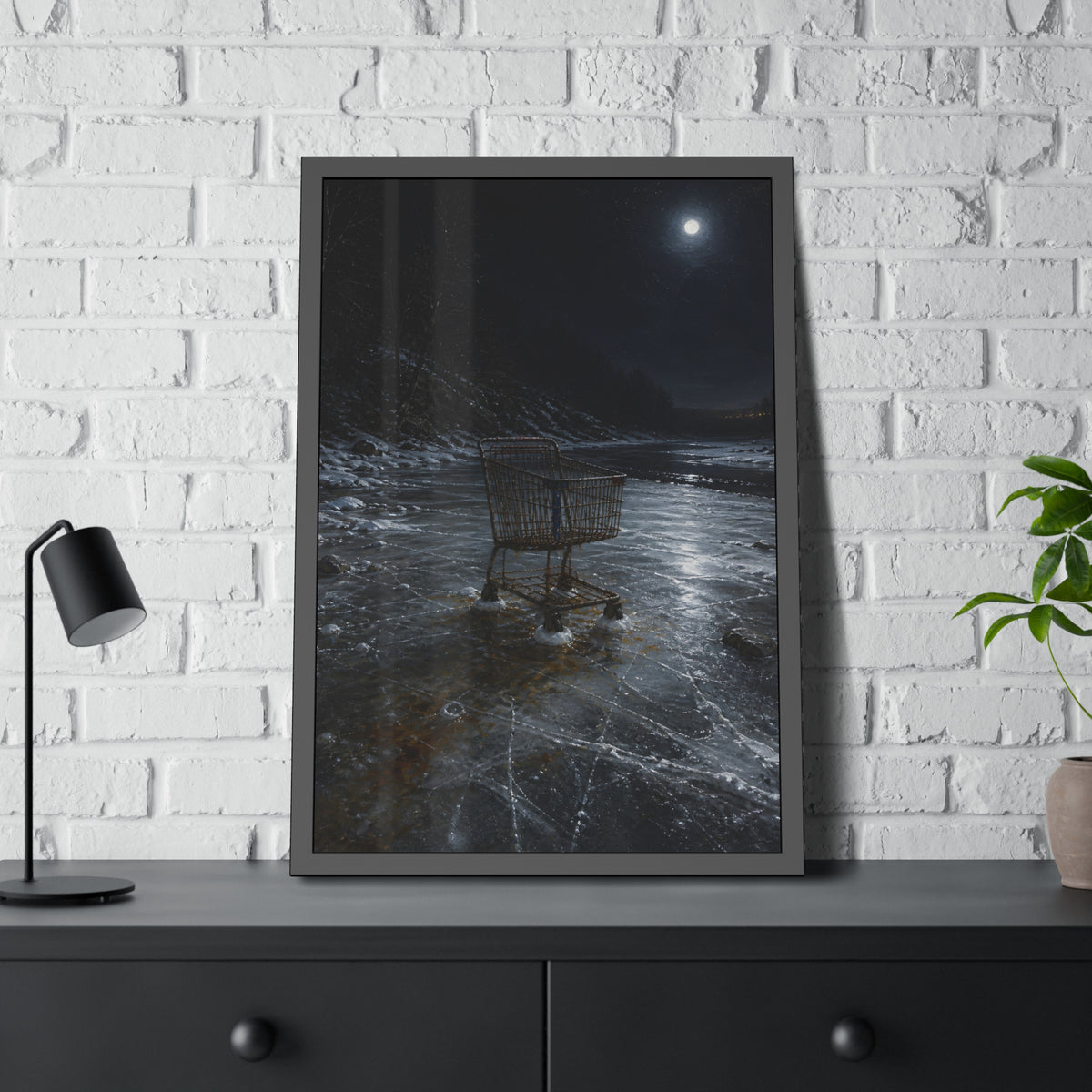 A rusted shopping cart frozen into moonlit river ice. The Wintering in the Ice by Garabaggio, framed fine art print hanging in a room.