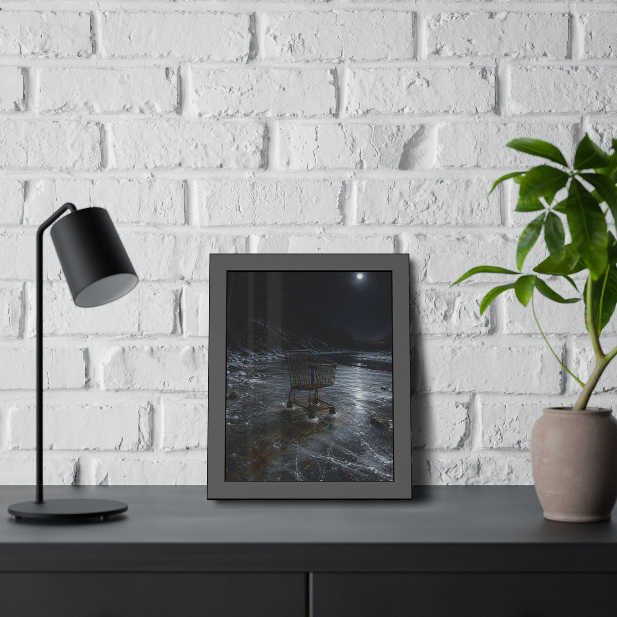 A rusted shopping cart frozen into moonlit river ice. The Wintering in the Ice by Garabaggio, framed fine art print hanging in a room.