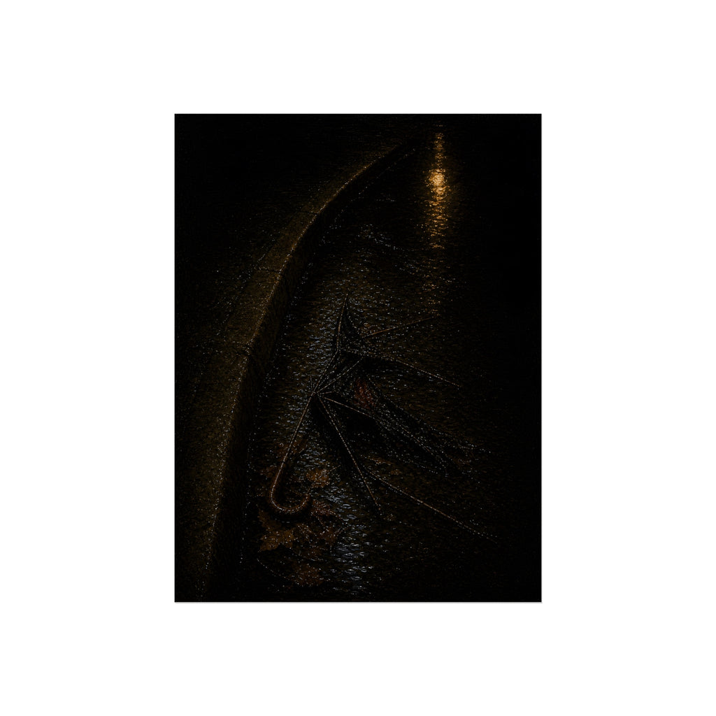 A collapsed umbrella in a dark wet gutter beside a curb, one distant light. The Procession in the Gutter by Garabaggio, fine art print, 12″ x 16″.