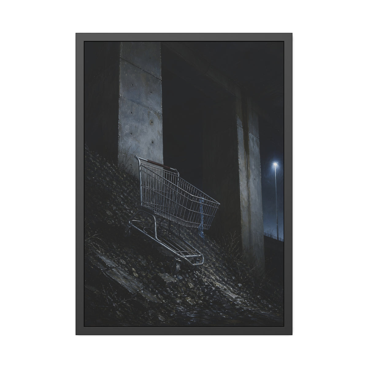 A shopping cart on a rocky slope under an overpass near a streetlamp. The Descent to the Underpass by Garabaggio, framed fine art print, 28″ x 40″.
