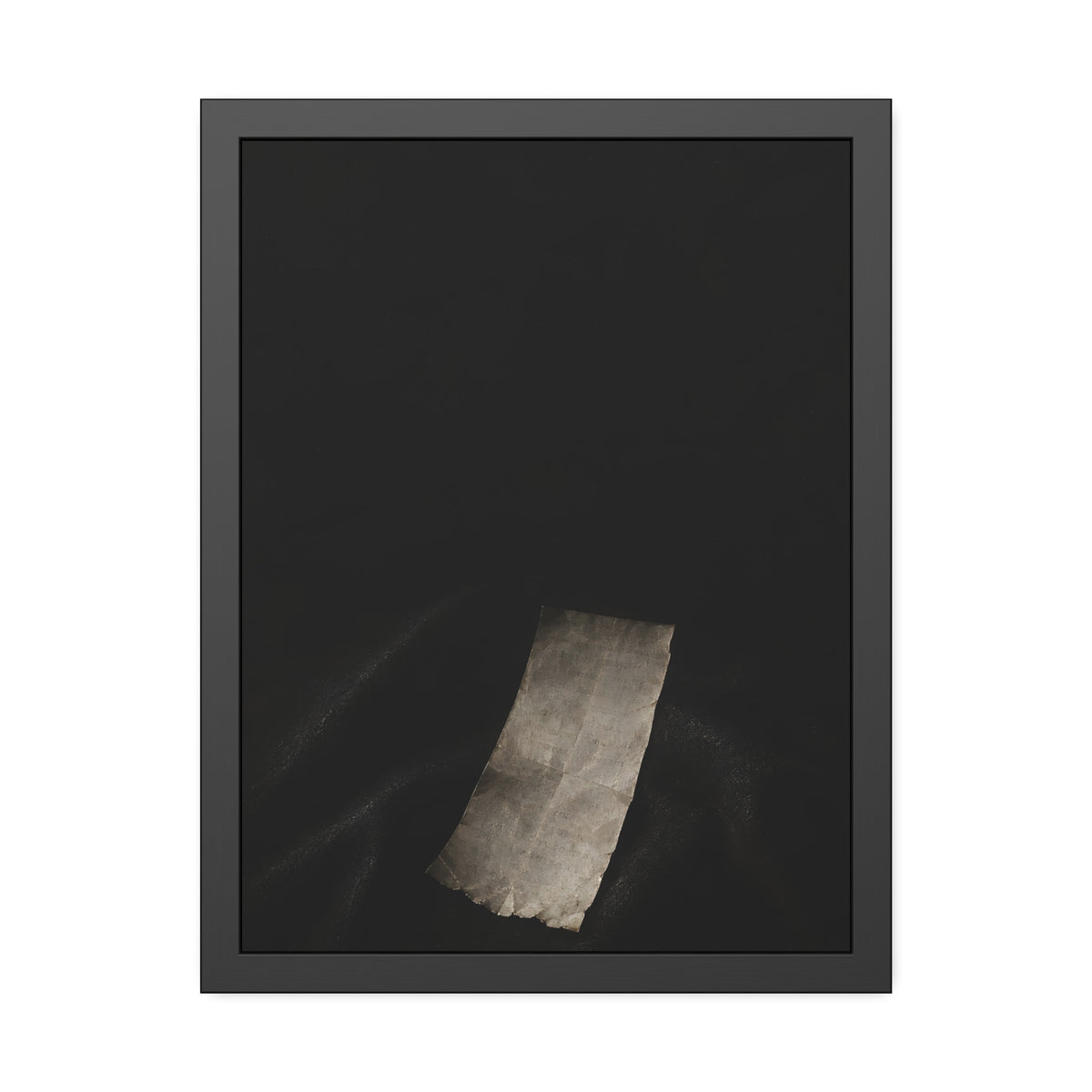 A blank paper slip on dark folded cloth in a narrow beam of light. The Blank Record by Garabaggio, framed fine art print, 18″ x 24″.