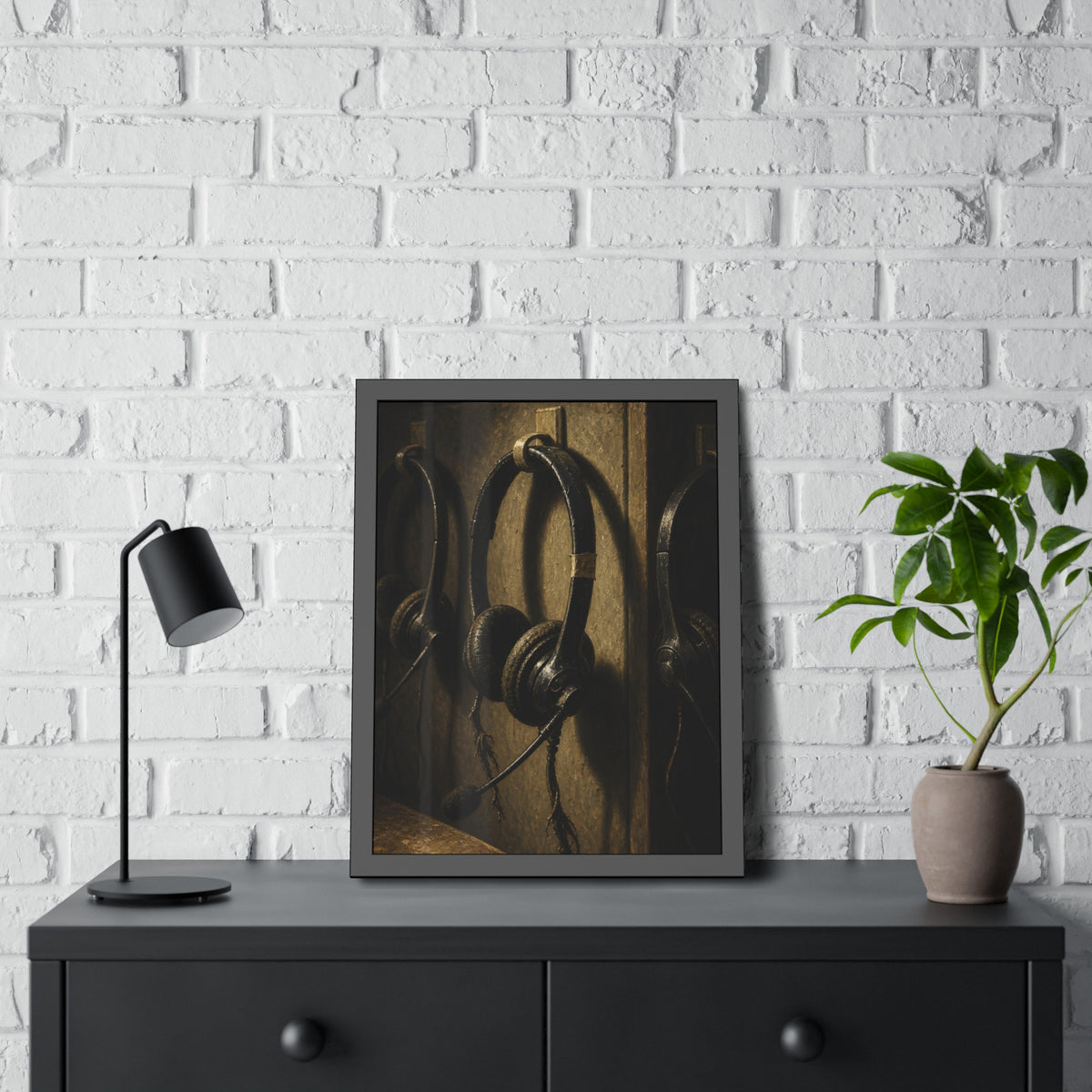 Three worn call center headsets hanging on wall hooks in dim light. The Headsets Left Hanging by Garabaggio, framed fine art print hanging in a room.