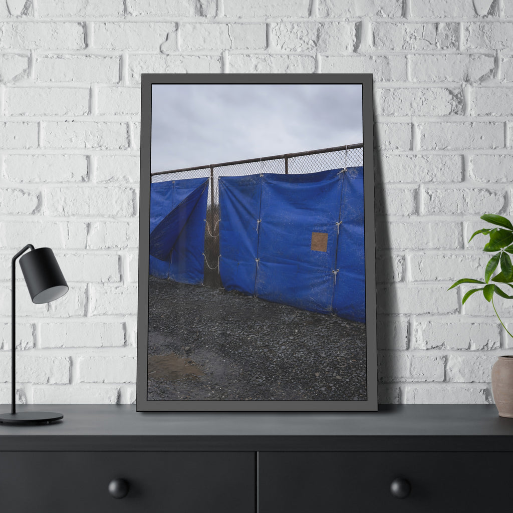 Blue tarps lashed to a chain link fence above gravel under grey sky. Drapery on the Fence by Garabaggio, framed fine art print hanging in a room.