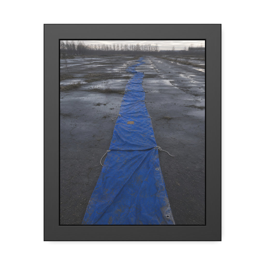A blue tarp laid in a long strip down a wet cracked lot under grey sky. The Long Ground Procession by Garabaggio, framed fine art print, 11″ x 14″.