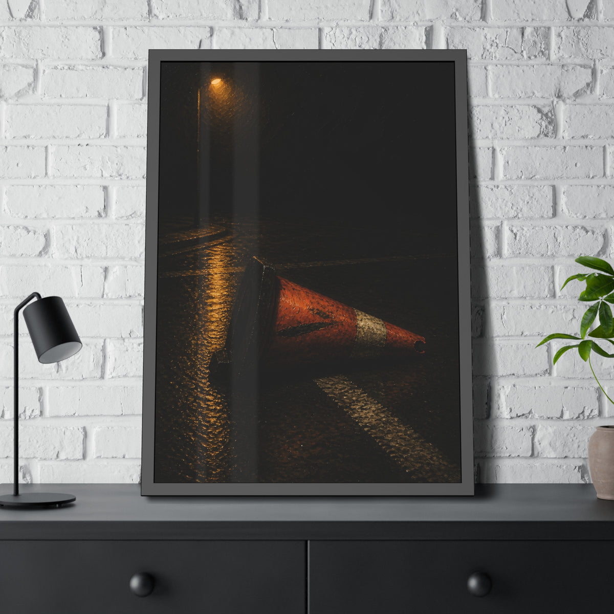 A toppled orange traffic cone on a wet road under a lone streetlight. The Taking by the Bumper by Garabaggio, framed fine art print hanging in a room.