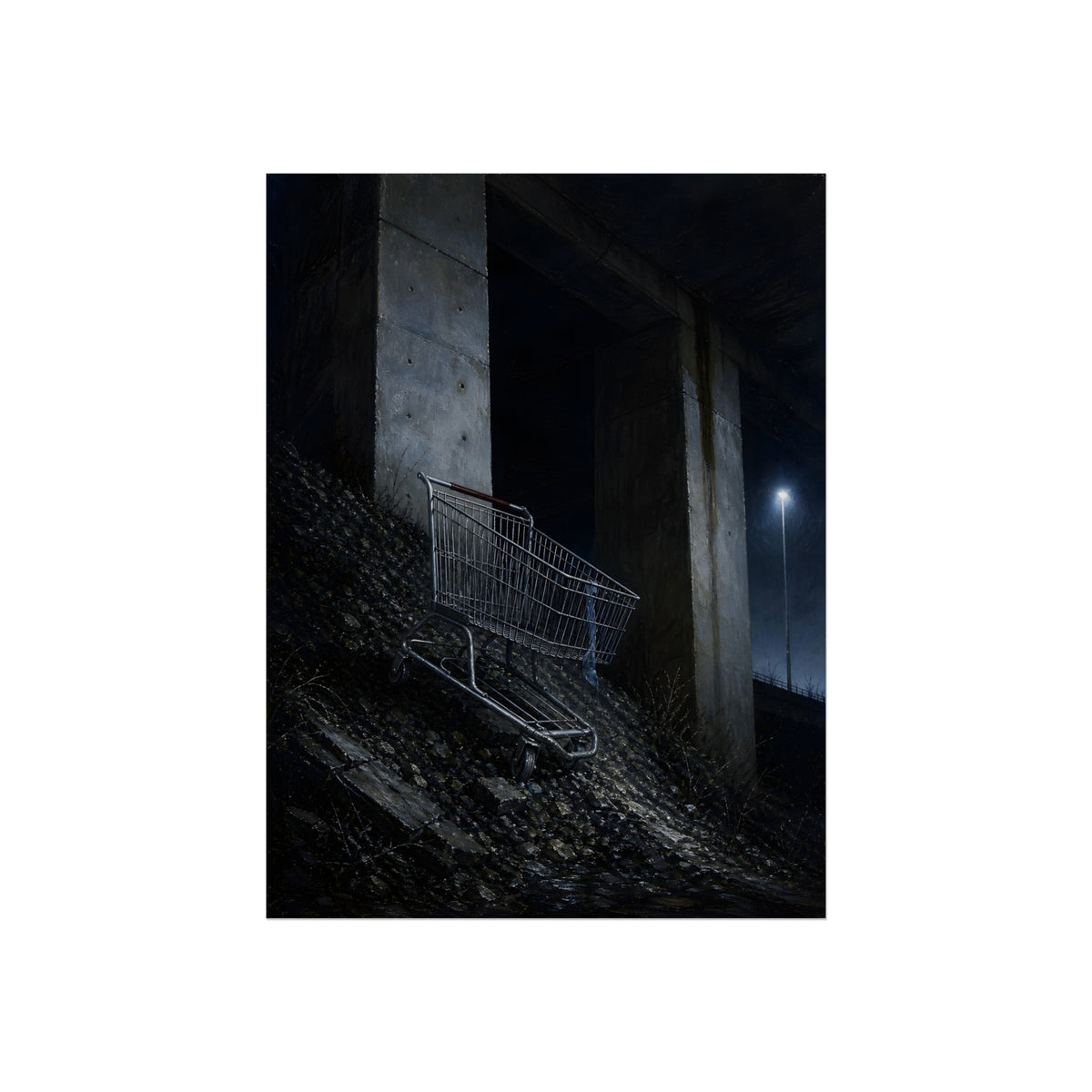 A shopping cart on a rocky slope under an overpass near a streetlamp. The Descent to the Underpass by Garabaggio, fine art print, 12″ x 16″.