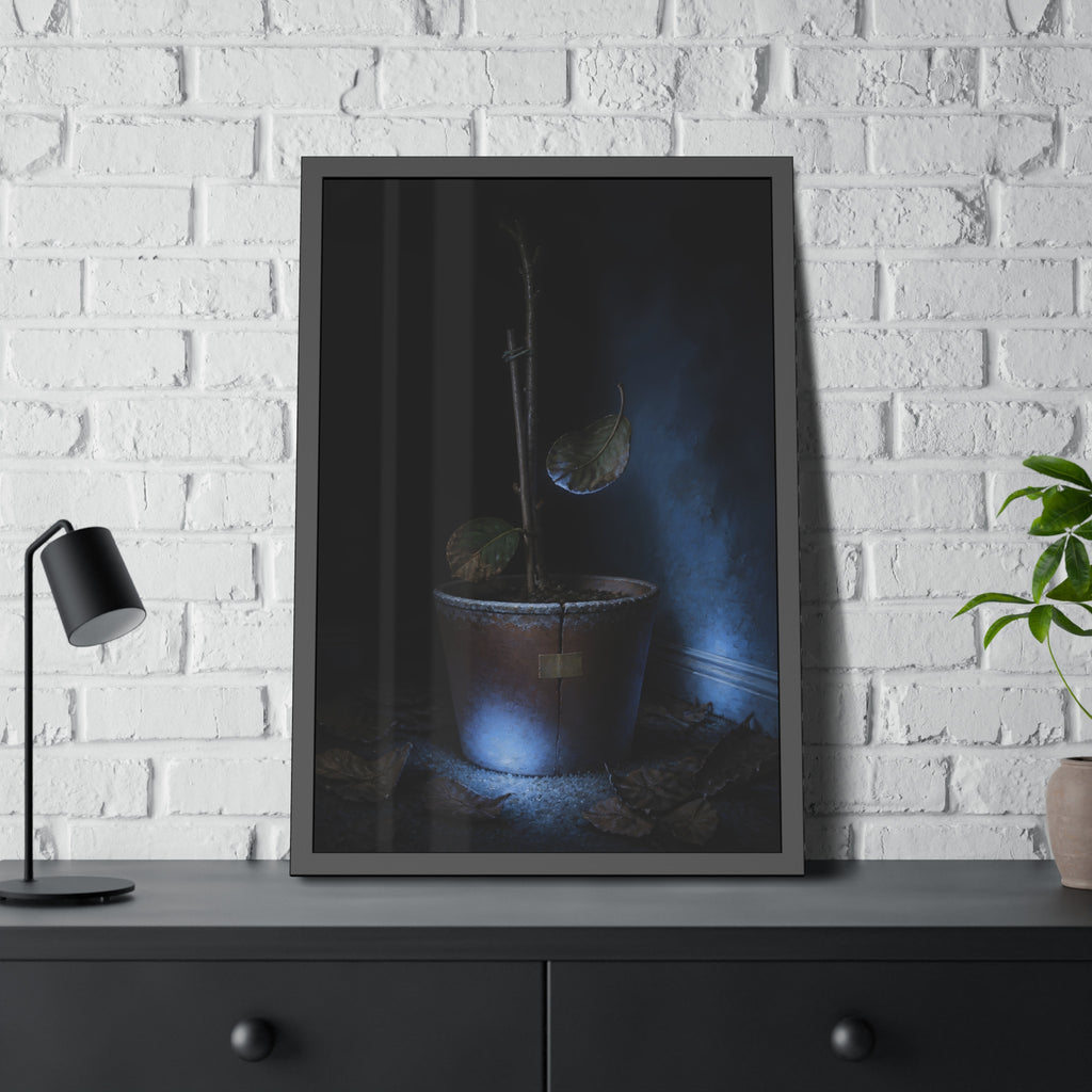 A bare potted plant dropping a leaf, dead leaves on the floor. The Leaf Lets Go by Garabaggio, framed fine art print hanging in a room.
