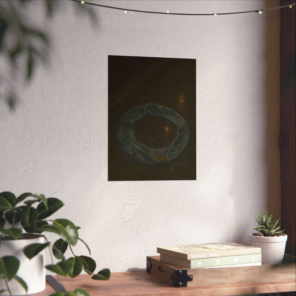 A deflated ring float holding rainwater on wet pavement at night. The Basin of Rain (Pool Float) by Garabaggio, fine art print hanging in a room.