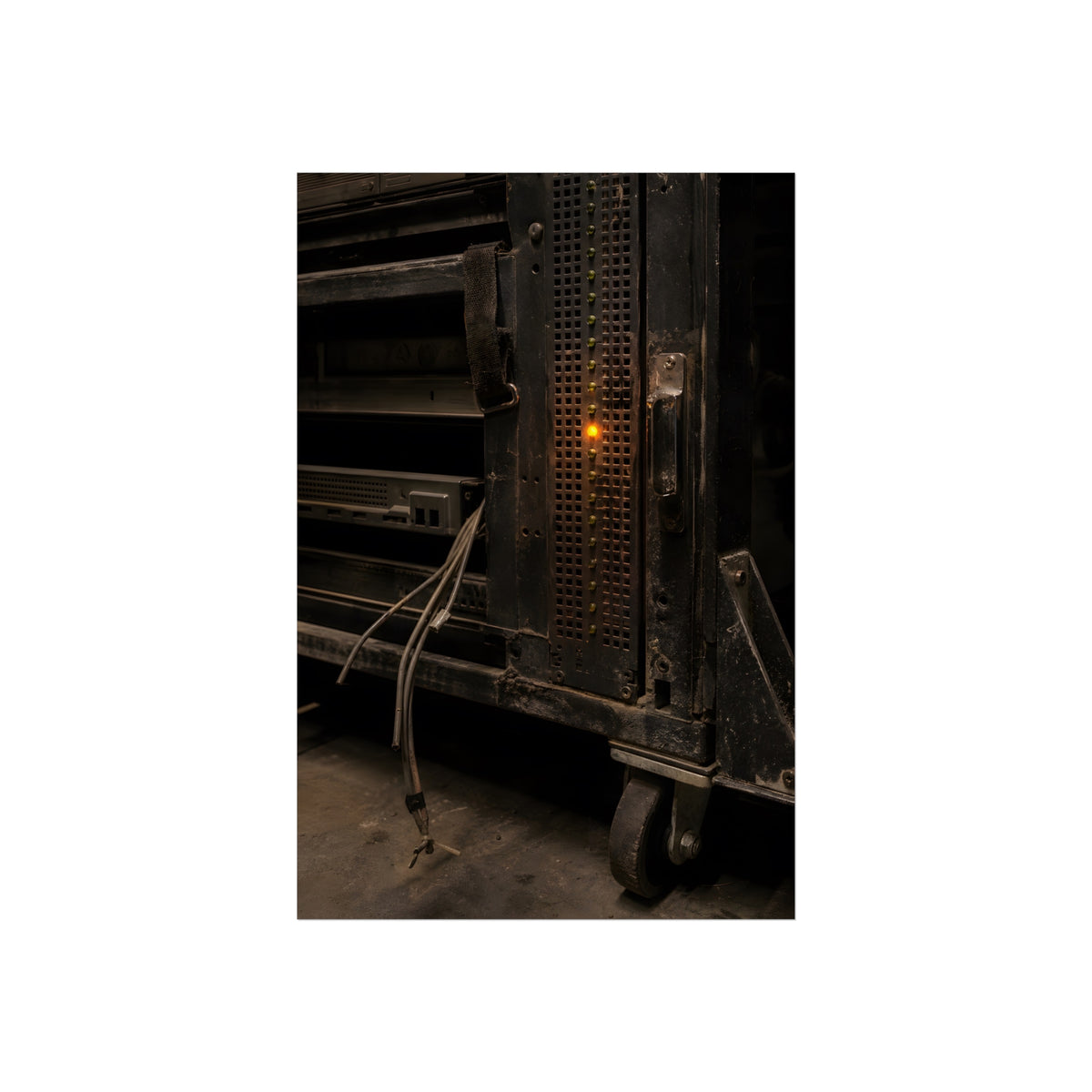 A single amber light among green LEDs on a grimy server rack. The Amber Fault by Garabaggio, fine art print, 24″ x 36″.