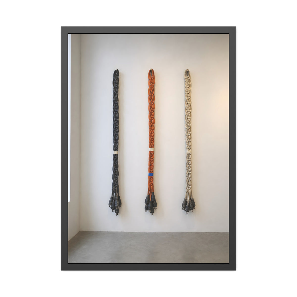 Three braided bundles of extension cords hung on a white gallery wall. The Braided Triptych by Garabaggio, framed fine art print, 28″ x 40″.
