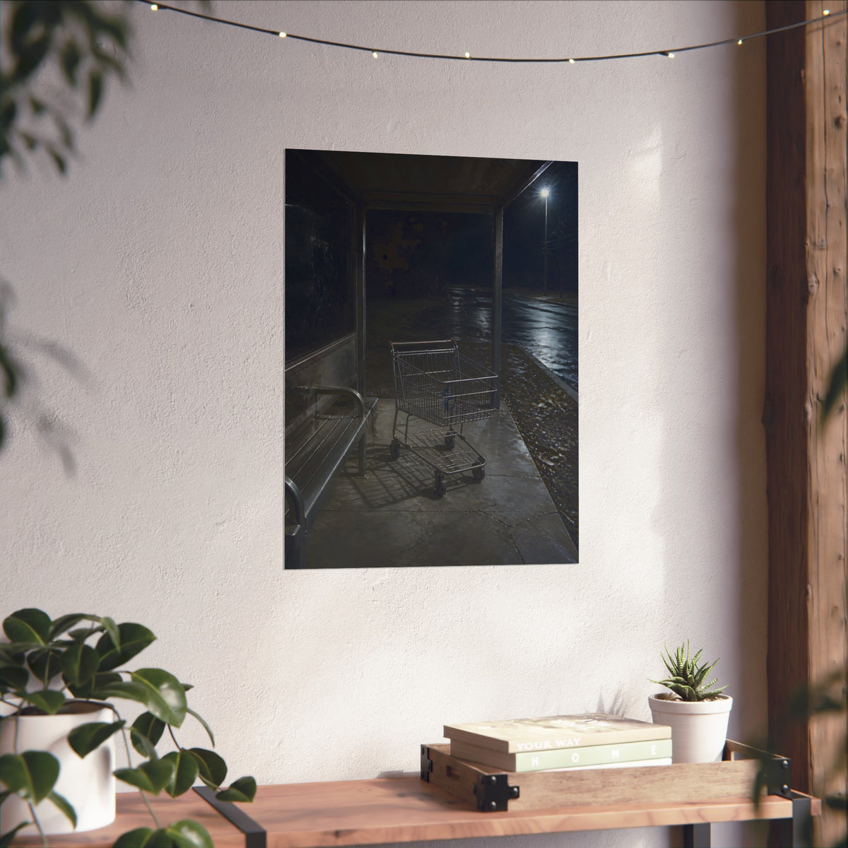 A shopping cart parked inside a bus shelter under a street lamp at night. The Rest at the Bus Shelter by Garabaggio, fine art print hanging in a room.