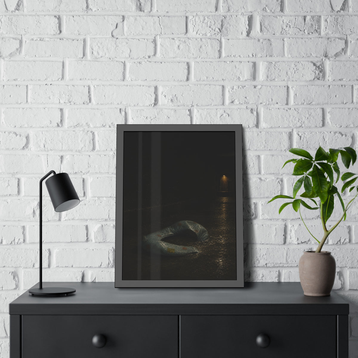 A deflated pool float ring on wet alley pavement, a lit doorway far behind. The Crossing of the Alley by Garabaggio, framed fine art print hanging in a room.