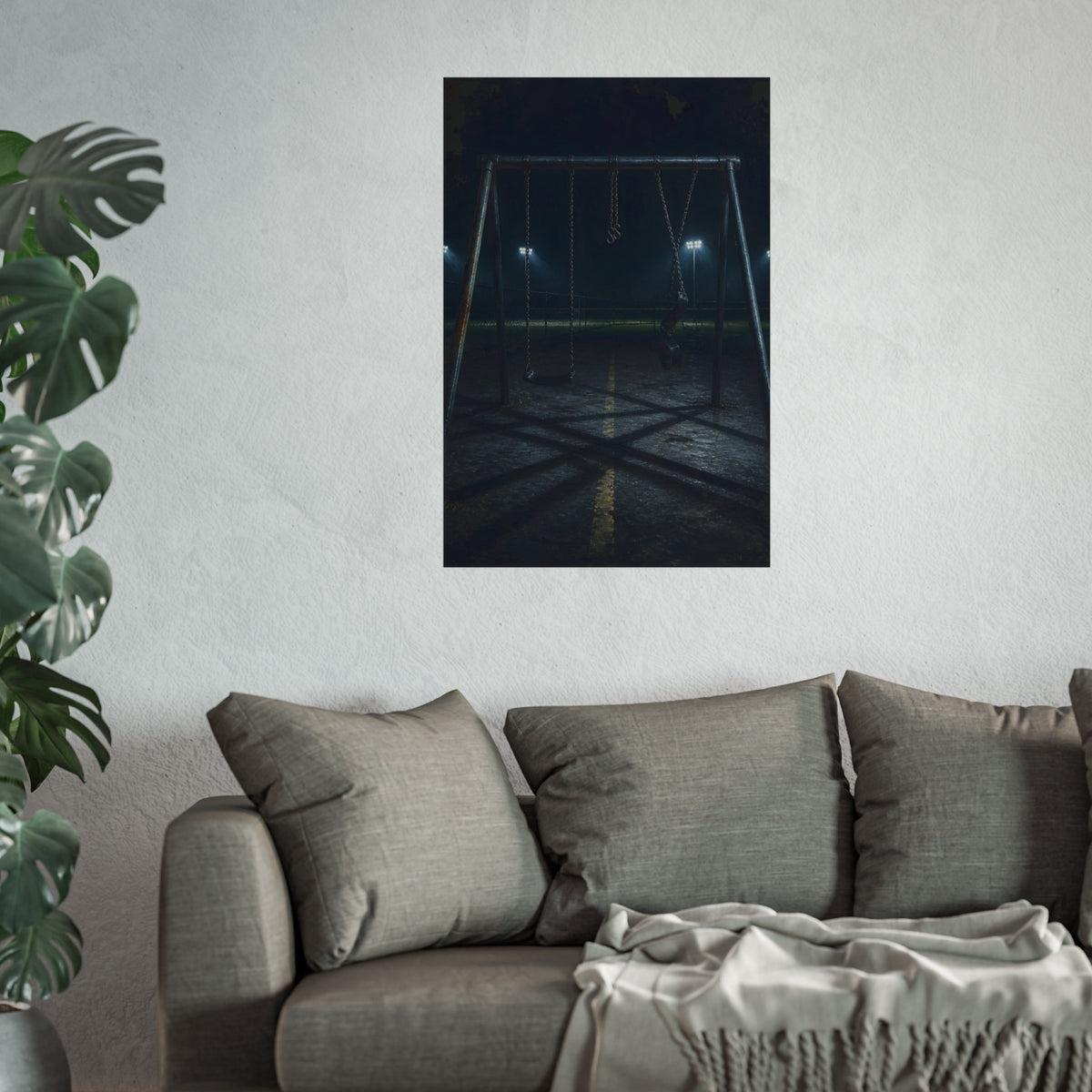 An empty swing set at night with field lights glowing behind it. The Ninth Hour: The Seat Still Moving by Garabaggio, fine art print hanging in a room.