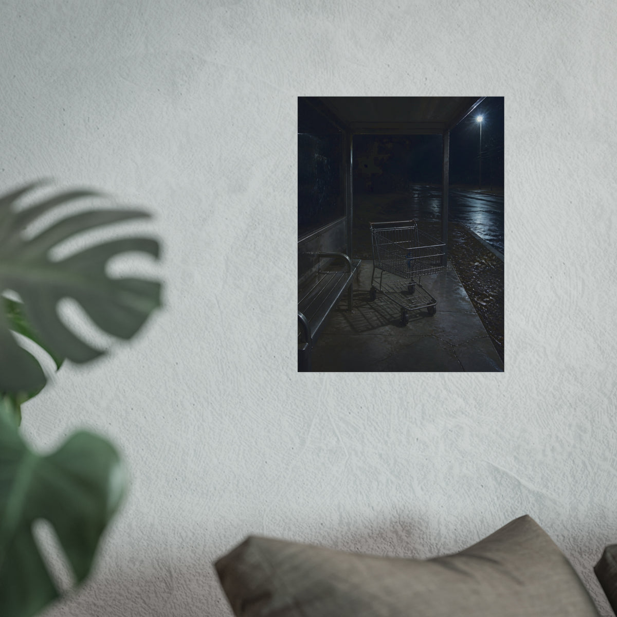 A shopping cart parked inside a bus shelter under a street lamp at night. The Rest at the Bus Shelter by Garabaggio, fine art print hanging in a room.