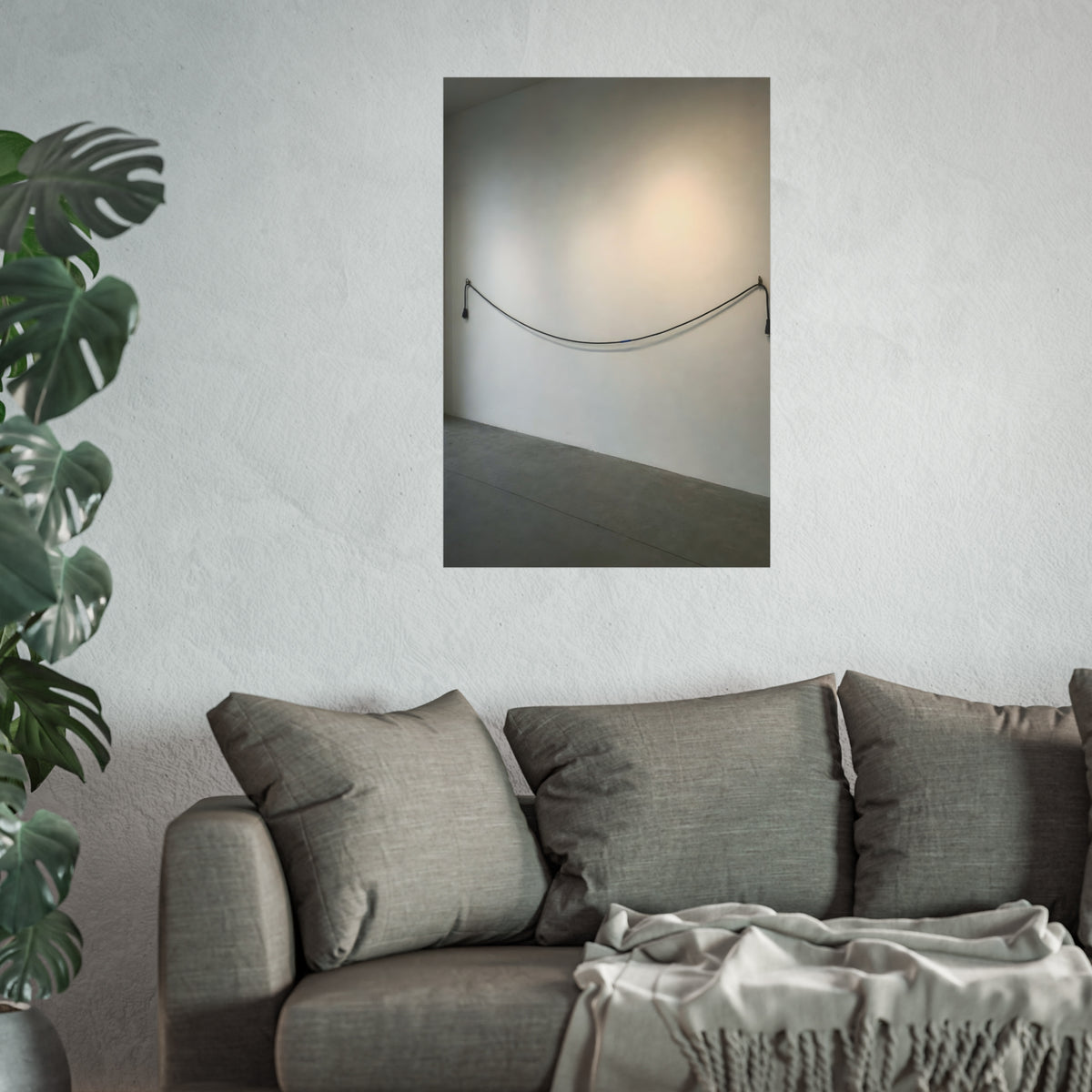 An extension cord hung in a long slack curve across a bare white wall. The Unplugged Line by Garabaggio, fine art print hanging in a room.