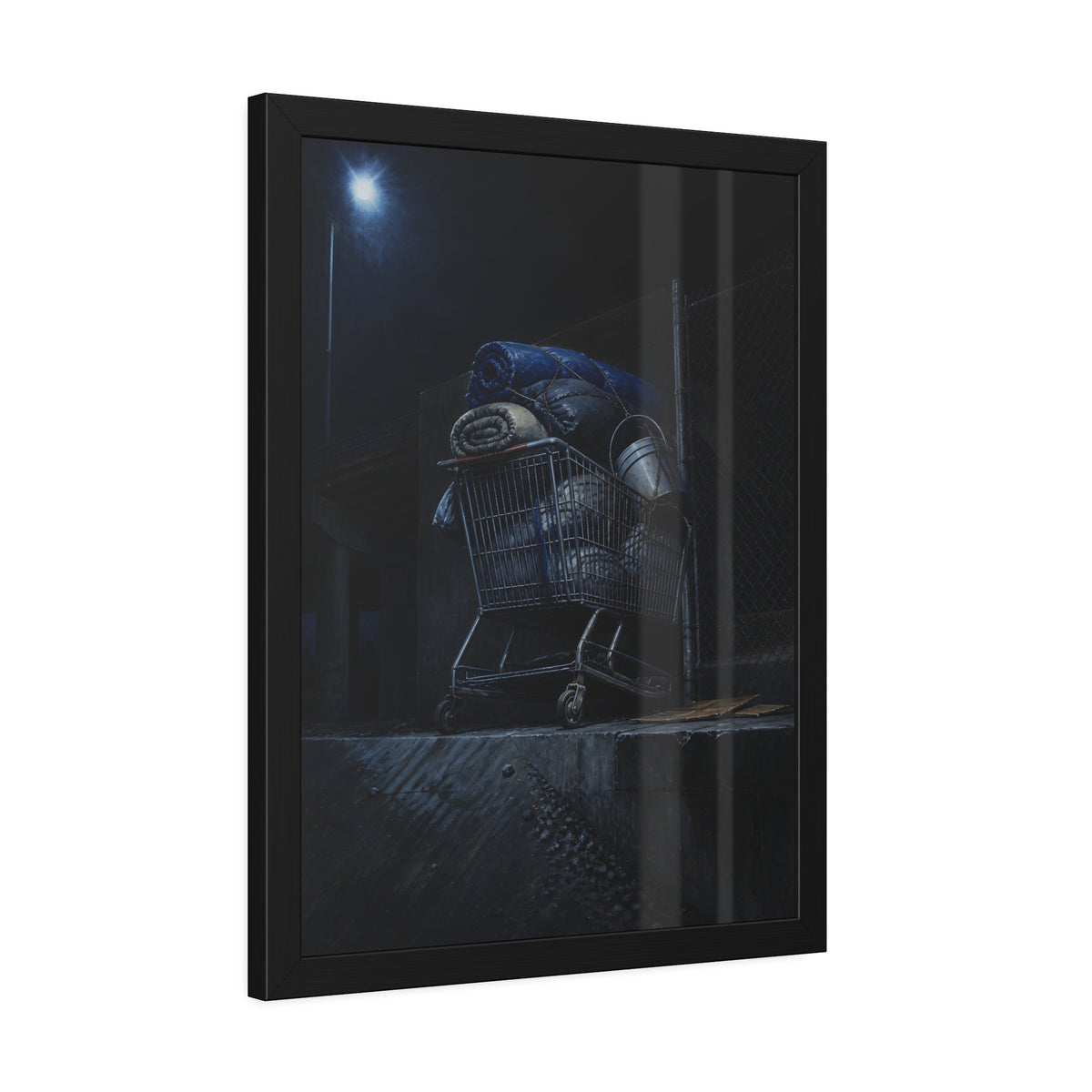 A shopping cart piled with bedding and buckets under a streetlamp. The Loading of Another Life by Garabaggio, framed fine art print hanging in a room.