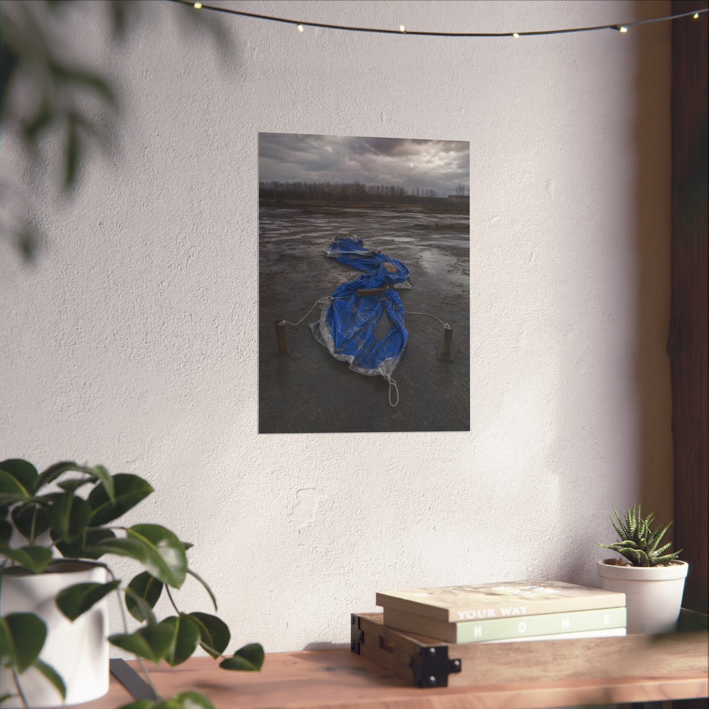 Collapsed blue tarp roped between two posts on wet cracked ground. Collapse Under Wind by Garabaggio, fine art print hanging in a room.