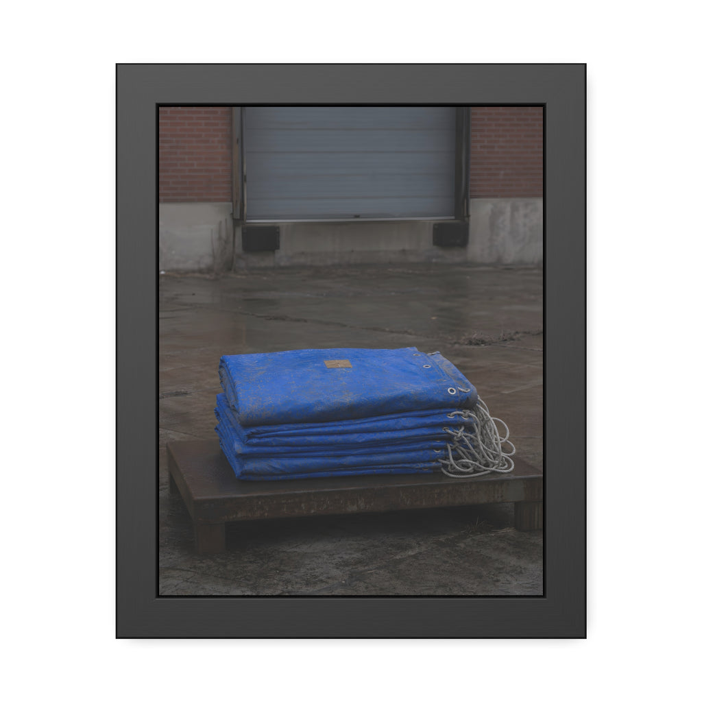 A folded blue tarp stacked on a low wooden platform by a loading dock. The Repaired Fold by Garabaggio, framed fine art print, 11″ x 14″.