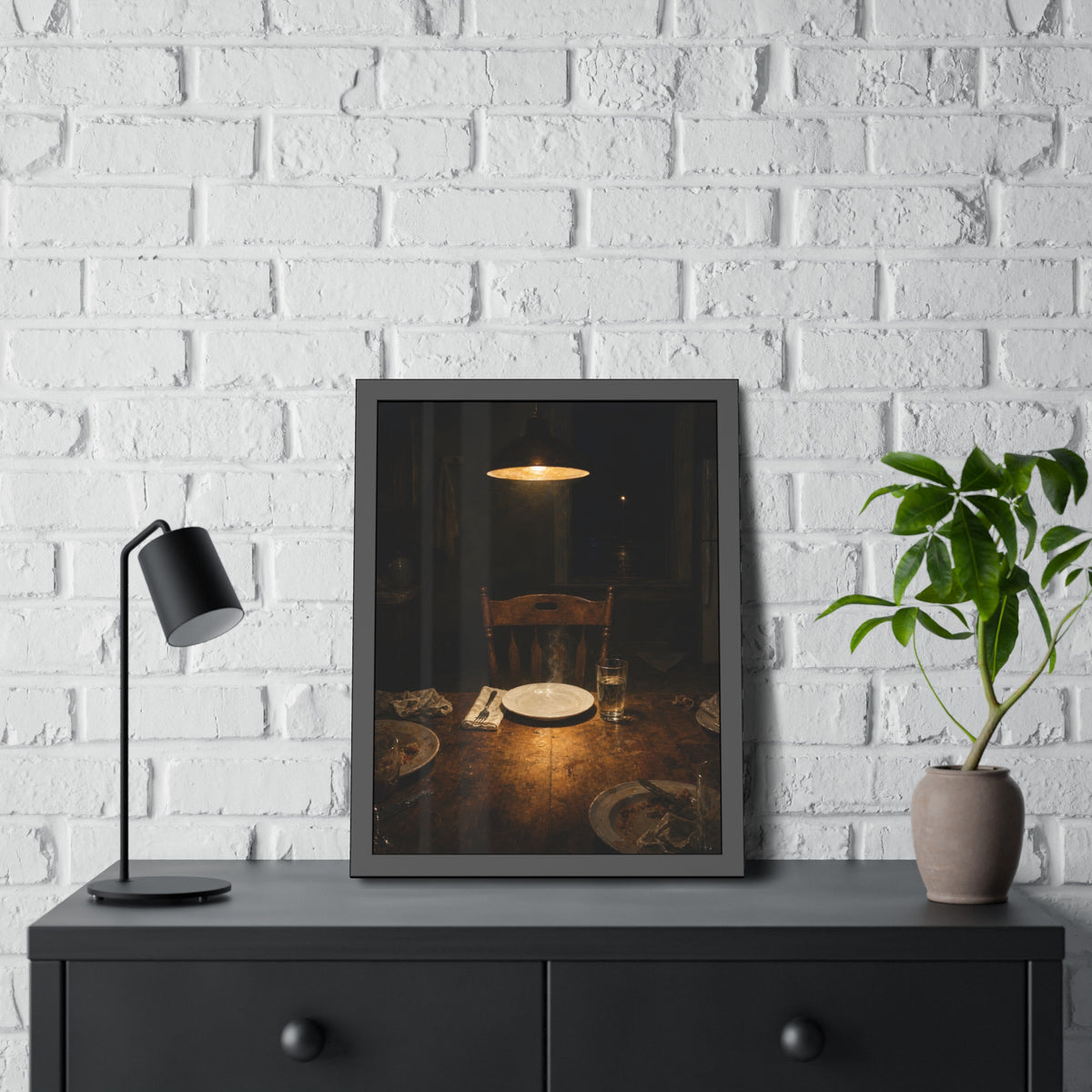 A clean plate and empty chair under a hanging lamp at a used dinner table. The Empty Seat at Dinner by Garabaggio, framed fine art print hanging in a room.