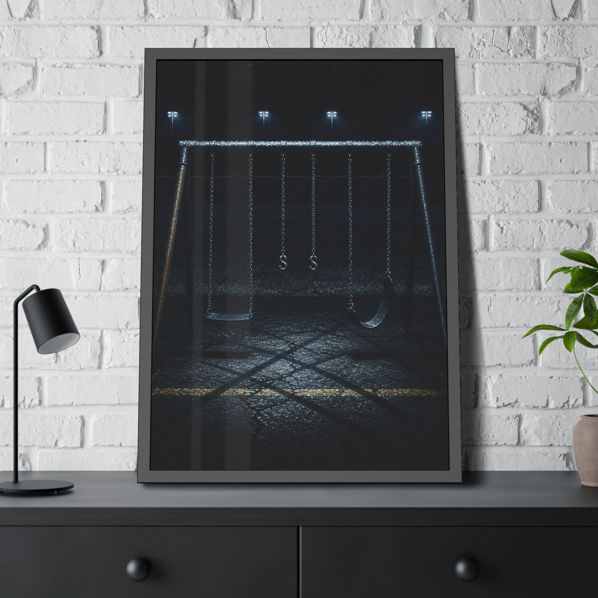 An empty swing set at night, chains still, floodlights far behind it. The Tenth Hour: The Chains Settle by Garabaggio, framed fine art print hanging in a room.