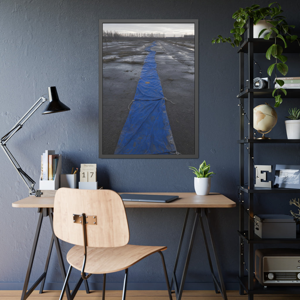 A blue tarp laid in a long strip down a wet cracked lot under grey sky. The Long Ground Procession by Garabaggio, framed fine art print hanging in a room.