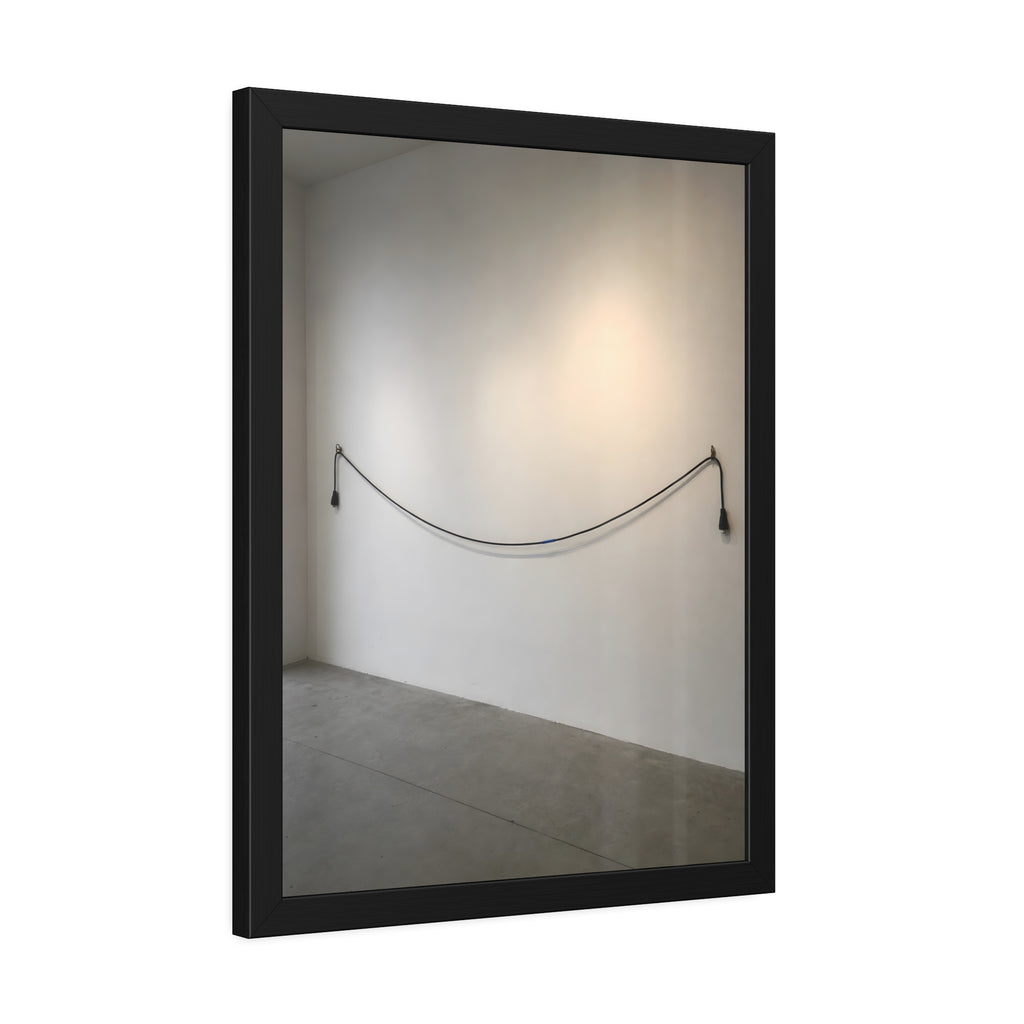 An extension cord hung in a long slack curve across a bare white wall. The Unplugged Line by Garabaggio, framed fine art print hanging in a room.