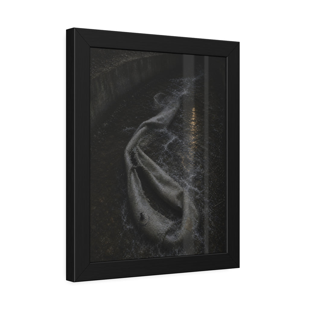 A deflated pool float caught in a concrete drainage channel of running water. The Release into Runoff by Garabaggio, framed fine art print hanging in a room.