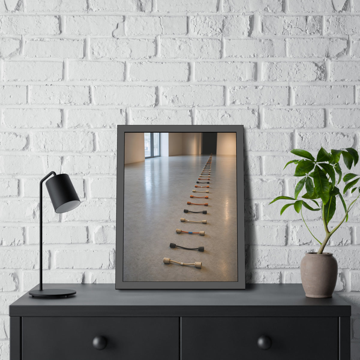 A long line of cut extension cord ends laid across a pale gallery floor. The Severed Procession by Garabaggio, framed fine art print hanging in a room.