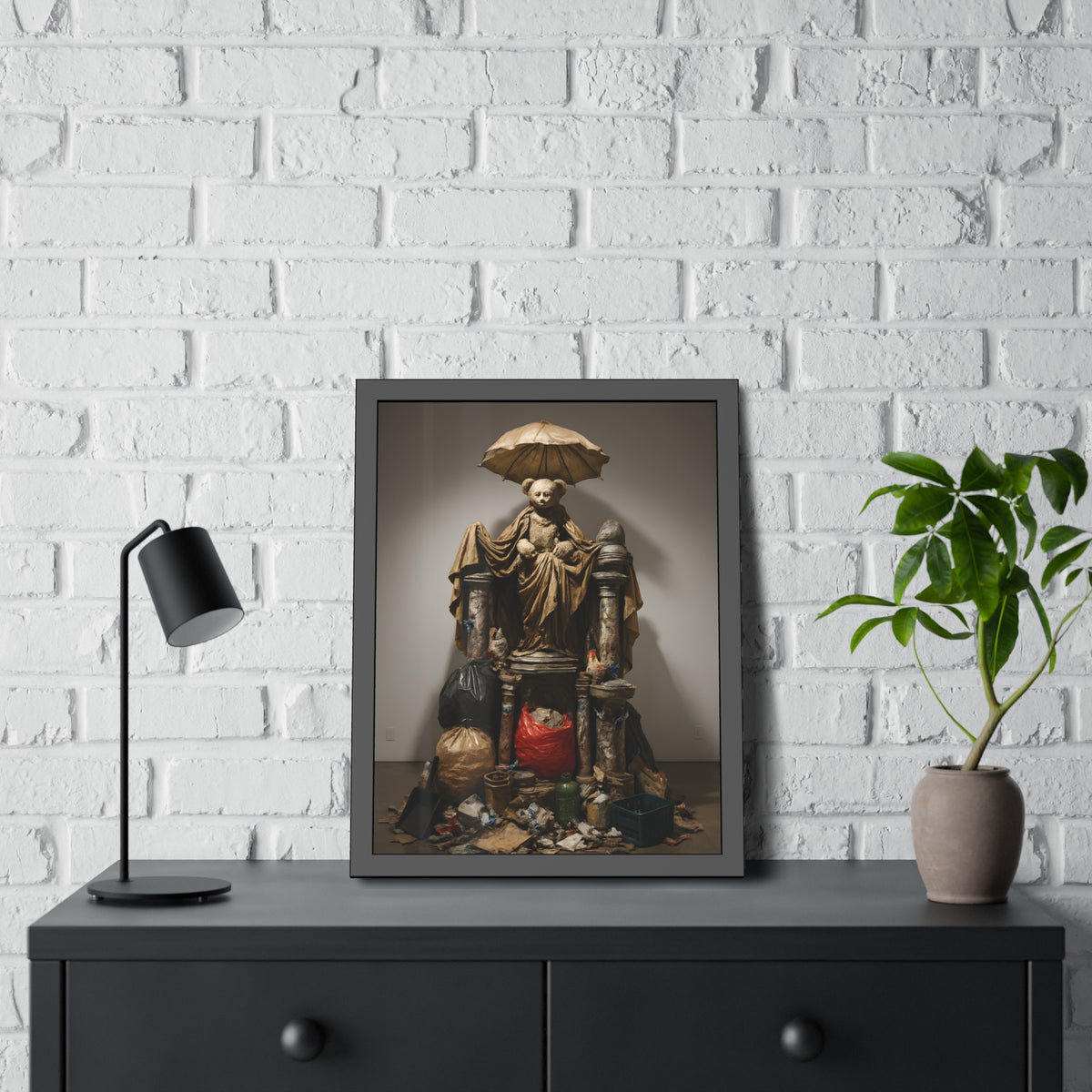 A teddy bear figure under an umbrella atop a pile of trash bags. Madonna of the Lost and Found by Garabaggio, framed fine art print hanging in a room.