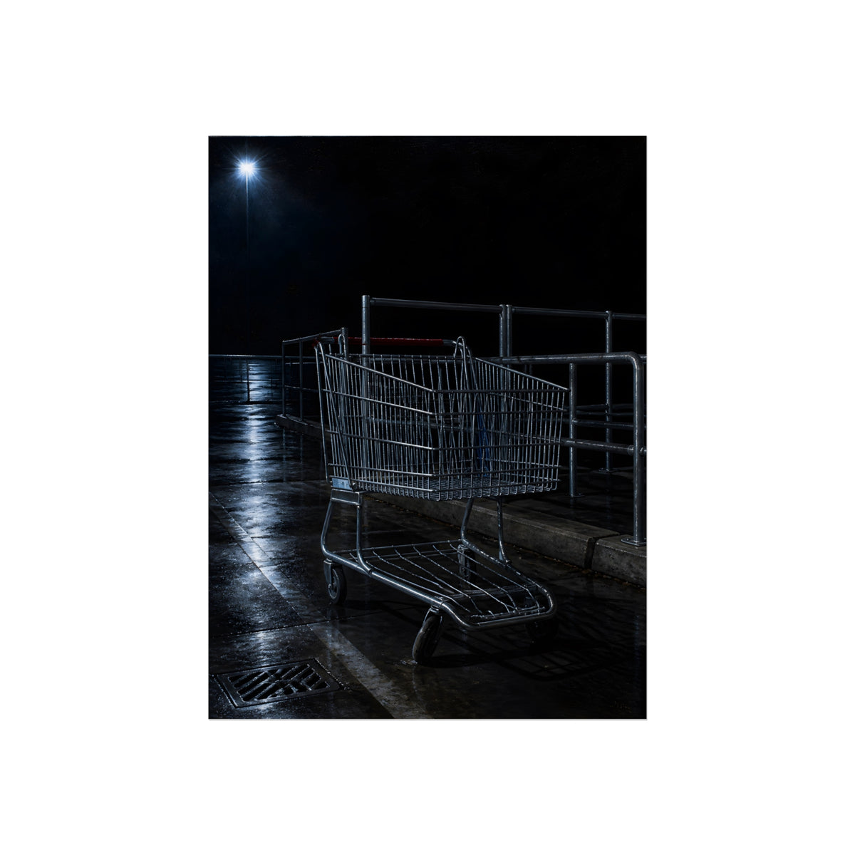 A shopping cart beside its corral on wet asphalt under a lot light. The Cart at the Corral by Garabaggio, fine art print, 12″ x 16″.