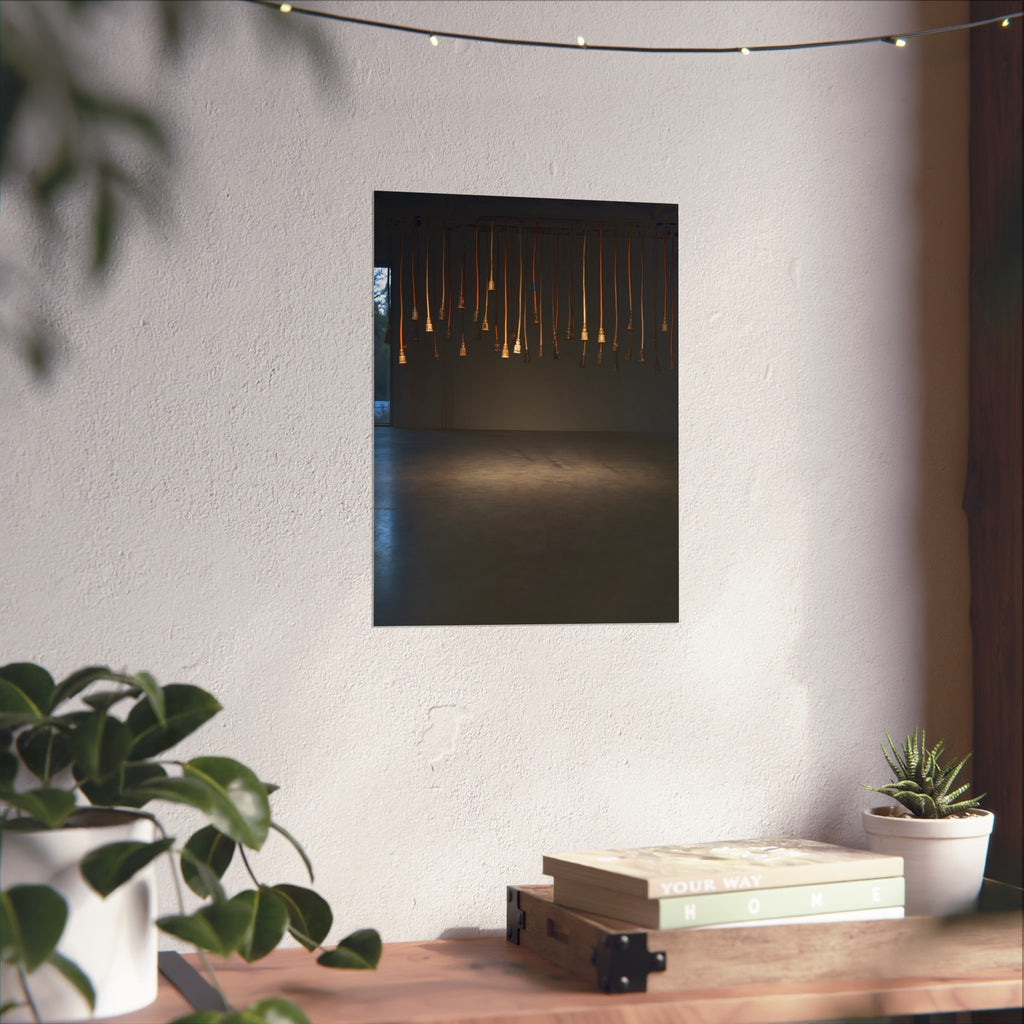 Extension cords hanging plug down from a ceiling in a dim room. All Ends, No Source by Garabaggio, fine art print hanging in a room.