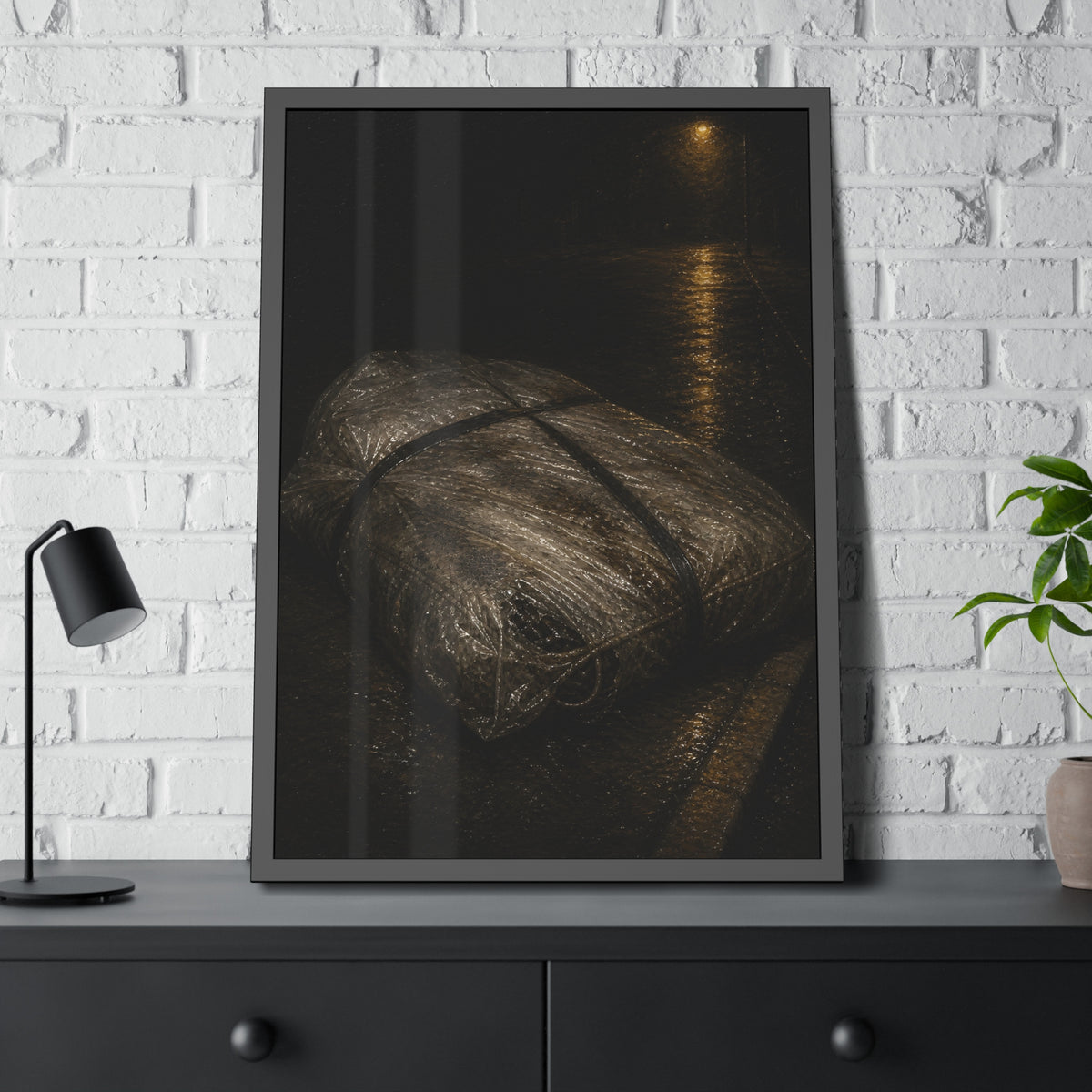 A mattress wrapped in plastic and strapped shut on a wet night street. The Municipal Shroud by Garabaggio, framed fine art print hanging in a room.