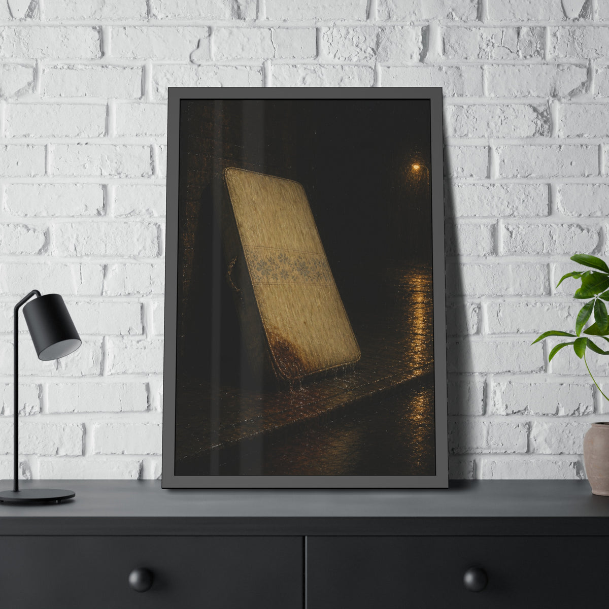 A stained mattress leaning against a wall in rain under a streetlamp. The First Rain by Garabaggio, framed fine art print hanging in a room.