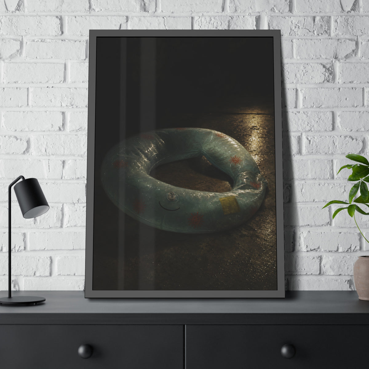 Deflated pool float ring on wet ground, lit from one side in the dark. After the Last Swim by Garabaggio, framed fine art print hanging in a room.