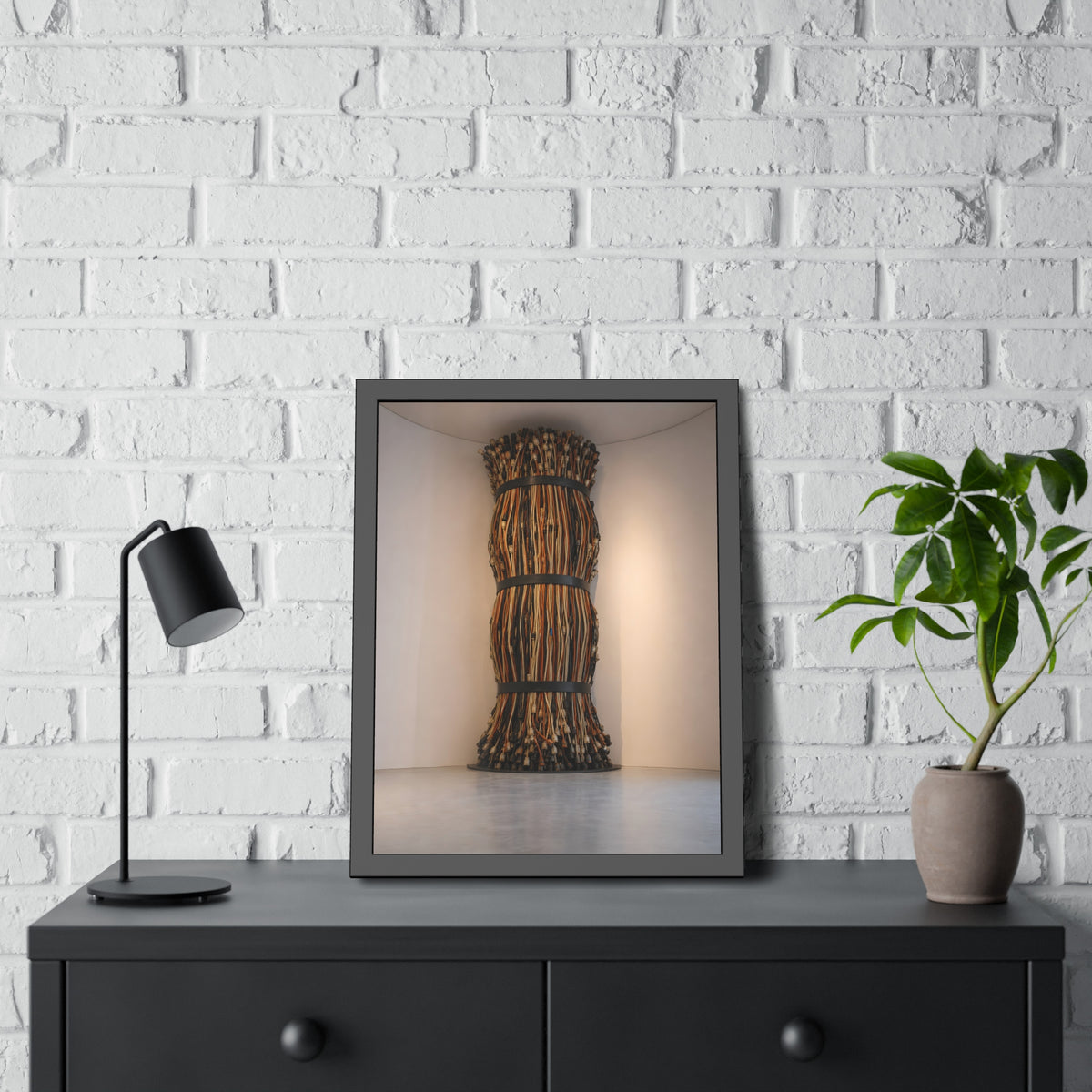A tall column of bundled cords strapped in three places in a gallery corner. The Bundled Apse by Garabaggio, framed fine art print hanging in a room.