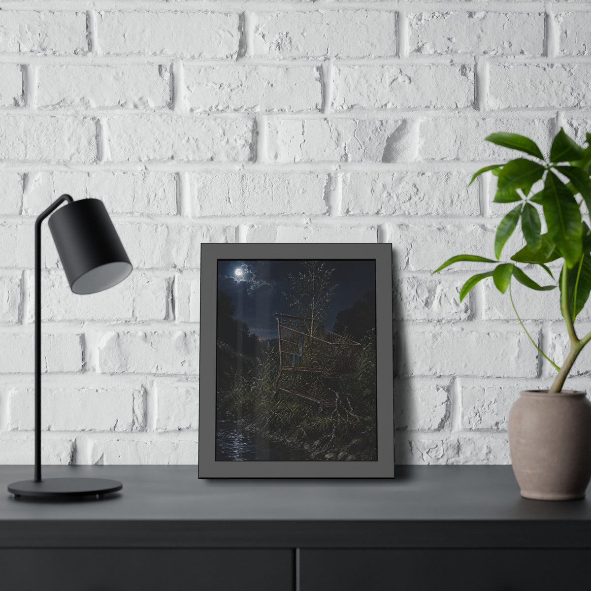 A shopping cart in creekside weeds with a sapling growing up through it. The Cart Grown Through by Garabaggio, framed fine art print hanging in a room.