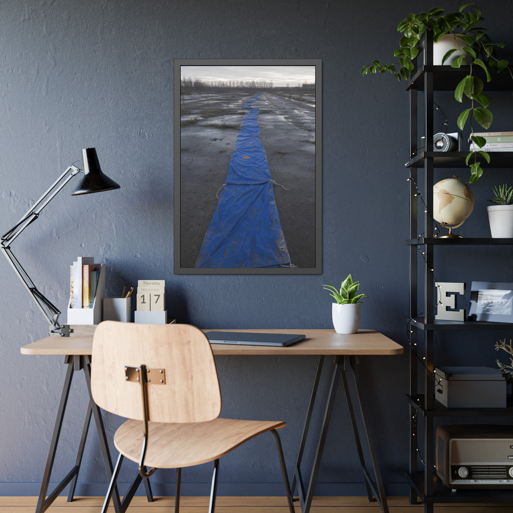 A blue tarp laid in a long strip down a wet cracked lot under grey sky. The Long Ground Procession by Garabaggio, framed fine art print hanging in a room.