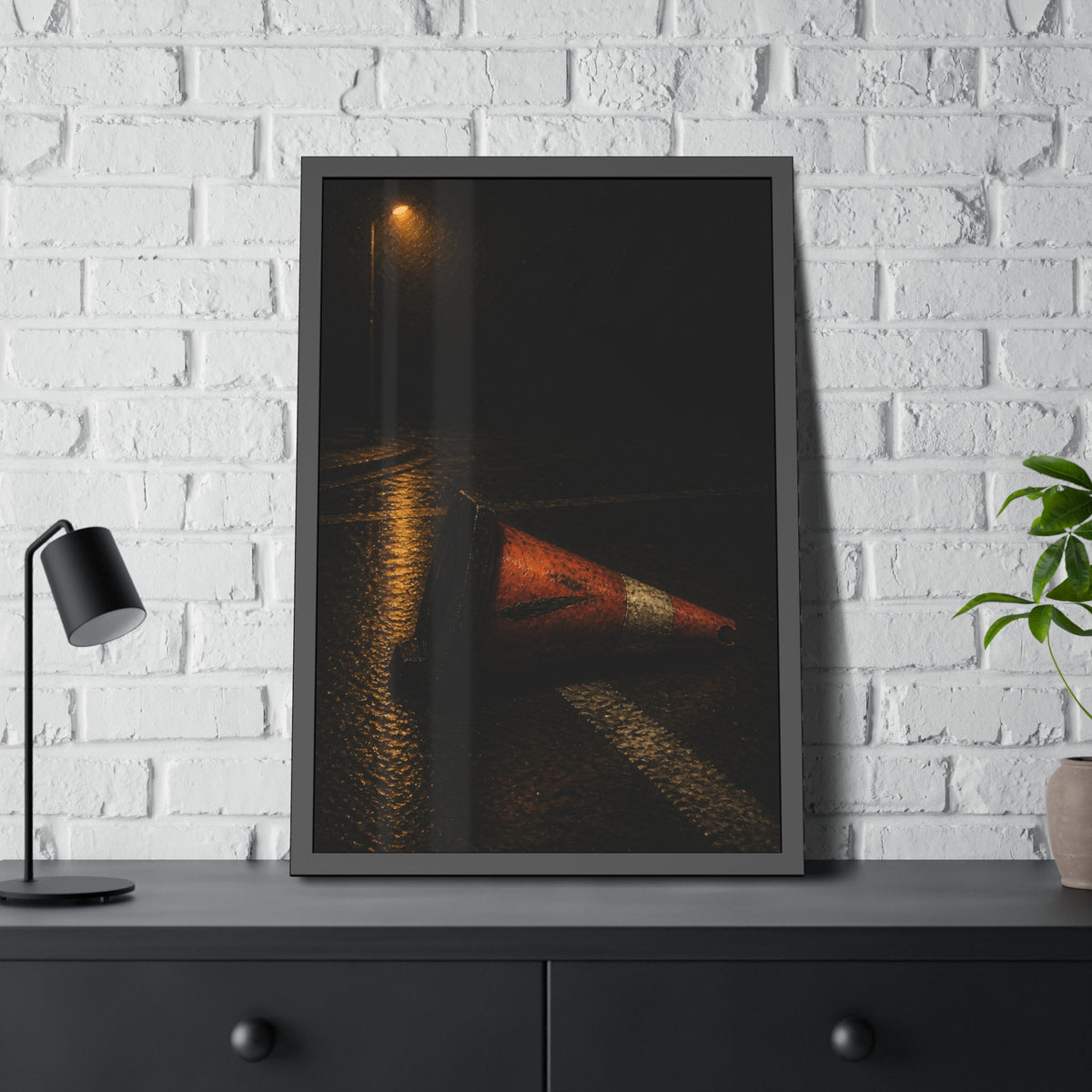 A toppled orange traffic cone on a wet road under a lone streetlight. The Taking by the Bumper by Garabaggio, framed fine art print hanging in a room.