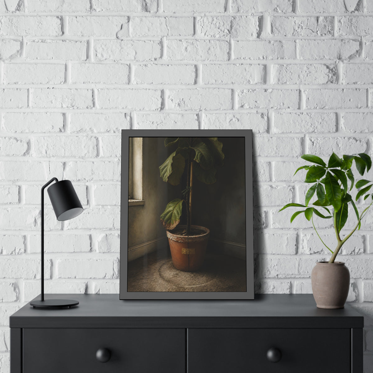 A leafy potted fig staked to a cane in a taped clay pot beside a window. The Corner by the Window by Garabaggio, framed fine art print hanging in a room.