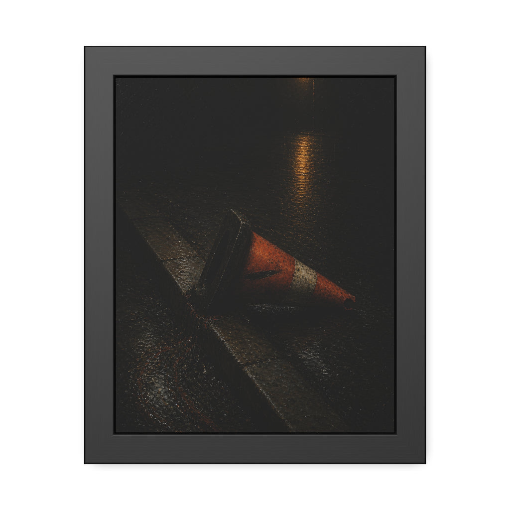 An orange traffic cone toppled on a wet curb under a distant streetlamp. The Dragging Through Rain by Garabaggio, framed fine art print, 11″ x 14″.