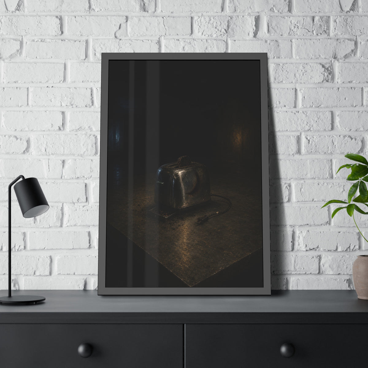 A scorched chrome toaster alone on a metal counter in a dark room. The Cooling on Steel by Garabaggio, framed fine art print hanging in a room.